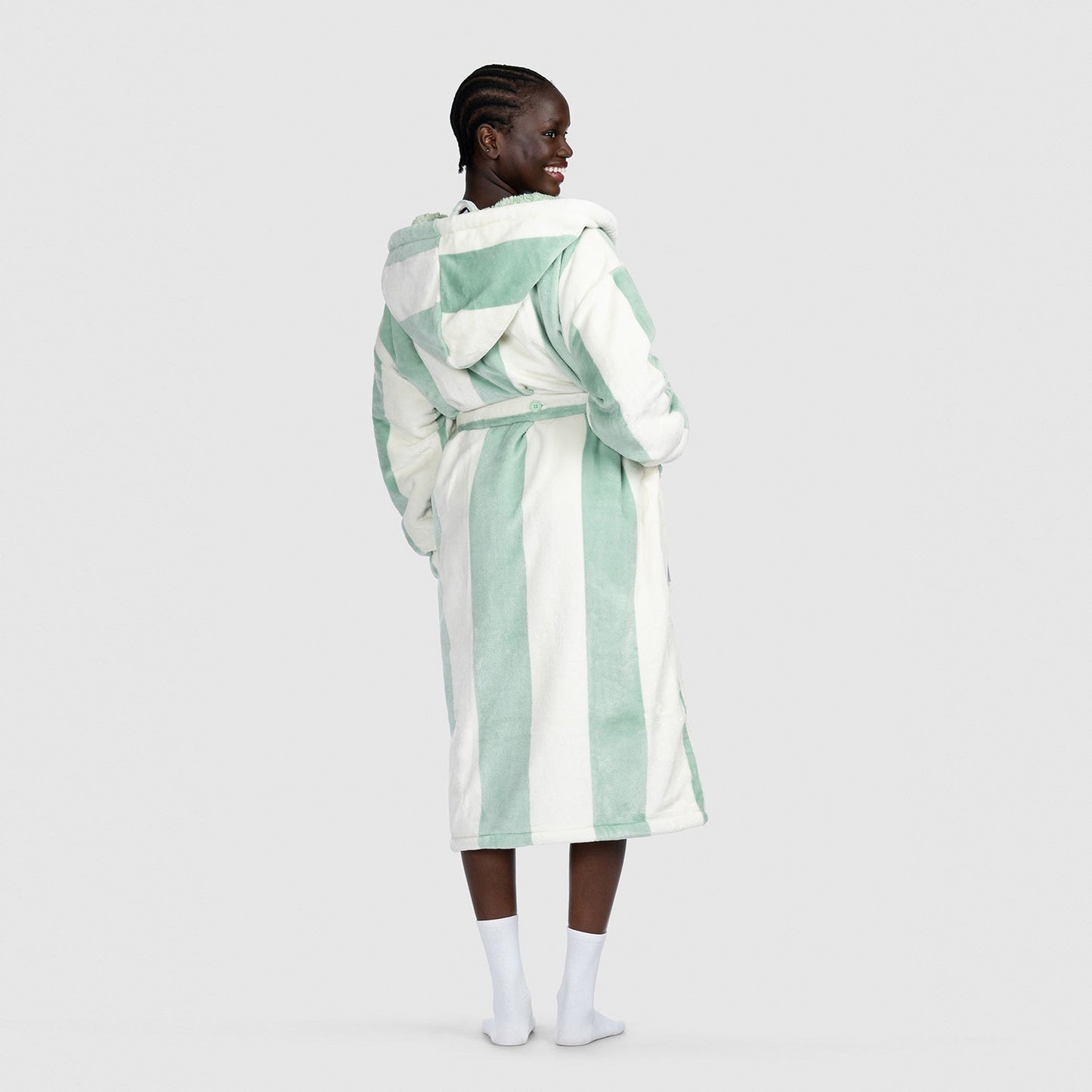 Person wearing a hooded robe with sage green and white vertical stripes, viewed from the back.