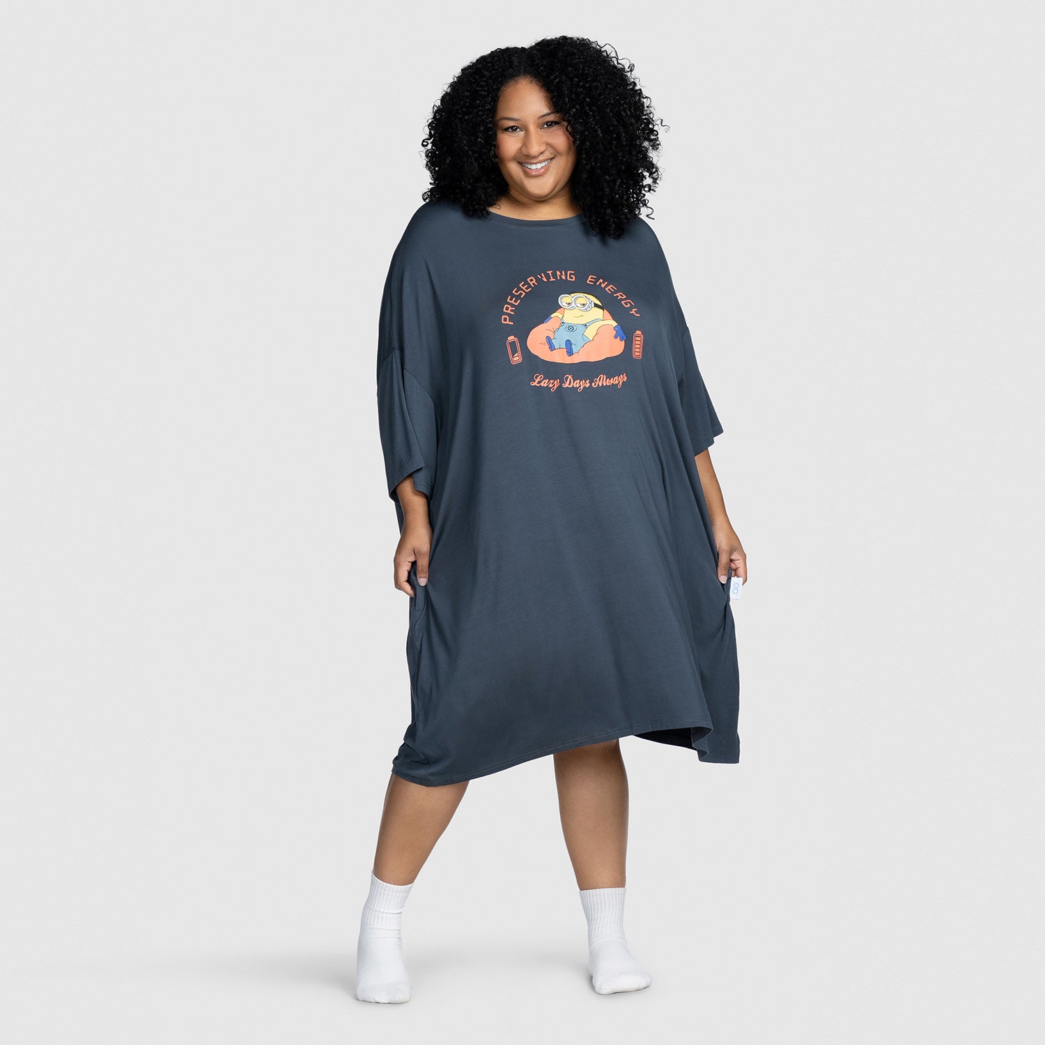 Woman wearing a dark oversized dress with a Minion character and text: "PRESERVING ENERGY Lazy Days Always"