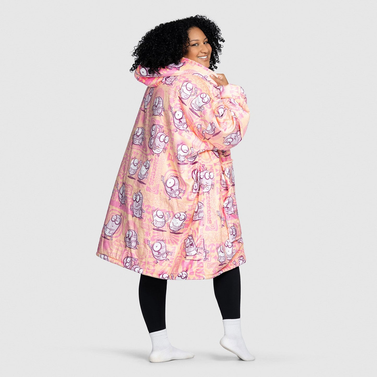 Woman wearing a pink Minions-themed sherbert robe with hood, standing and looking back