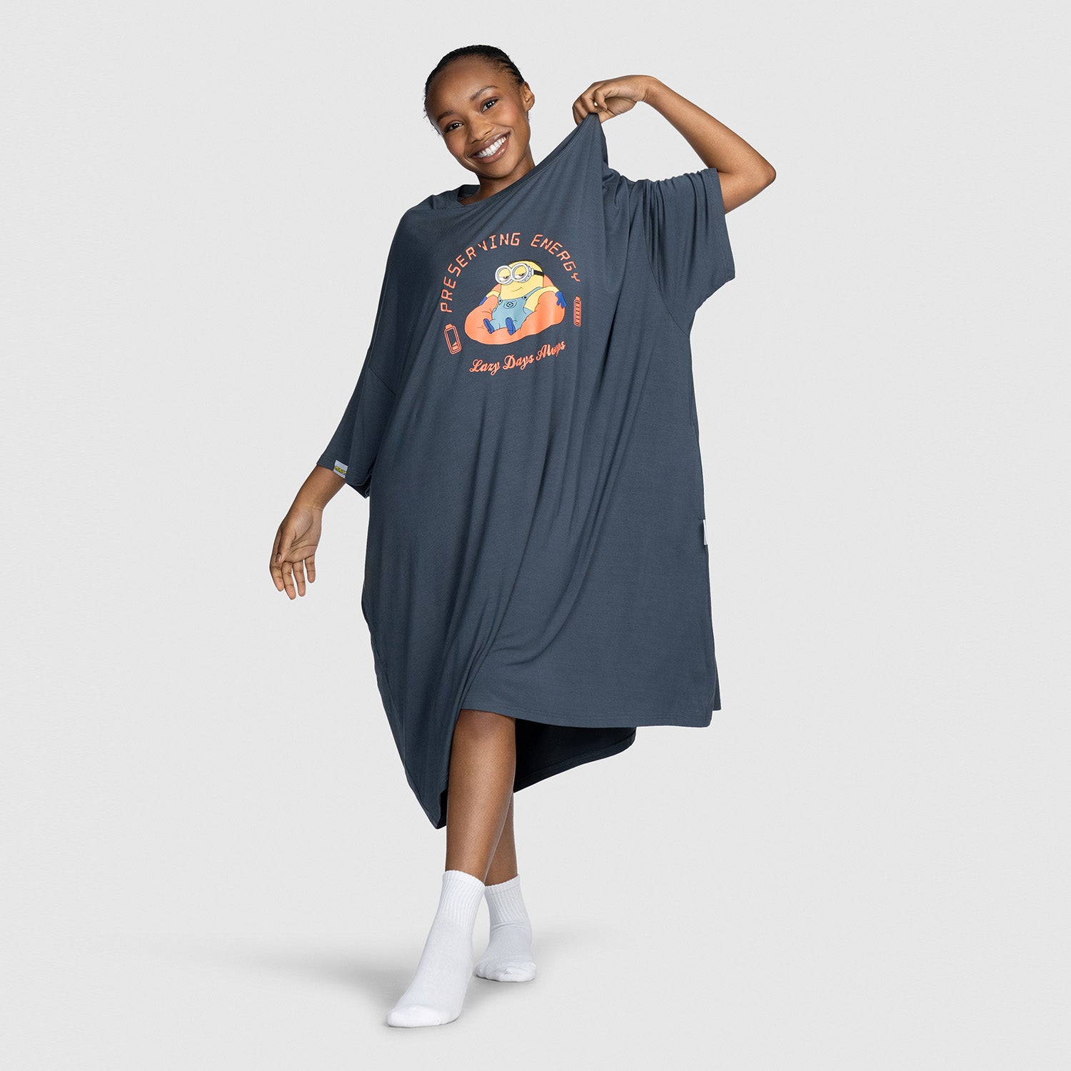 Woman wearing a dark oversized dress with a Minion character and text 'PRESERVING ENERGY Lazy Days Matter' printed on the front
