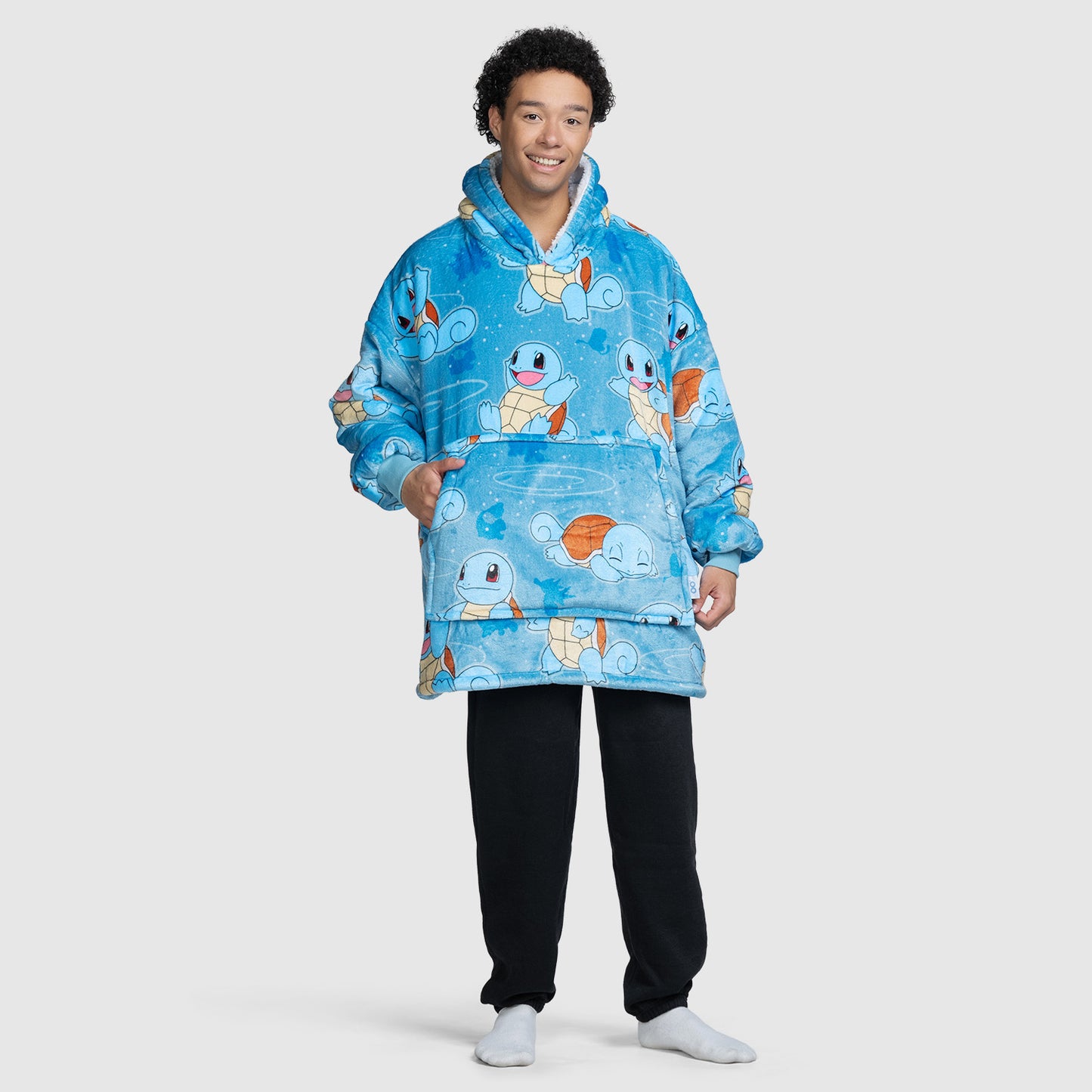 A person wearing a blue hoodie blanket covered with multiple images of the Pokémon character Squirtle in various poses.