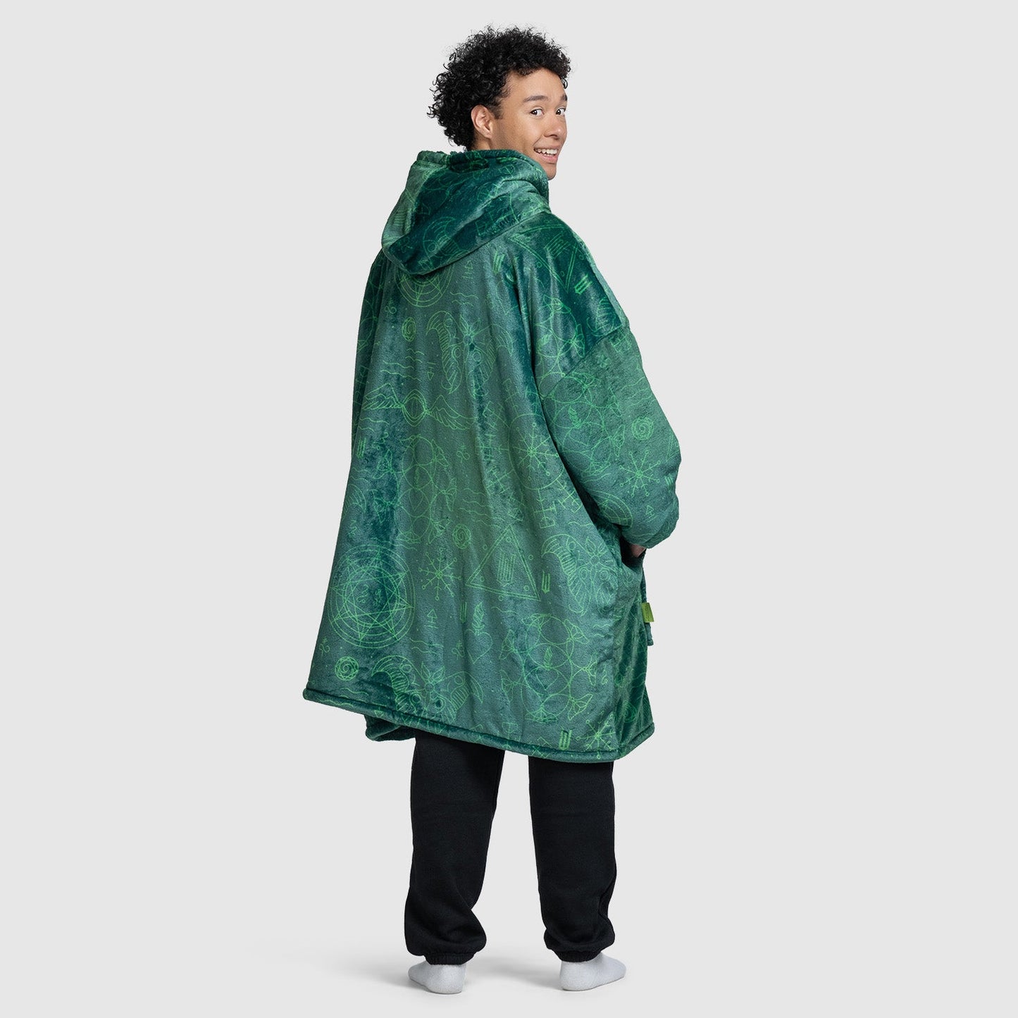 Man wearing a green patterned hooded jacket, standing with back turned and looking over shoulder; model is 5'11
