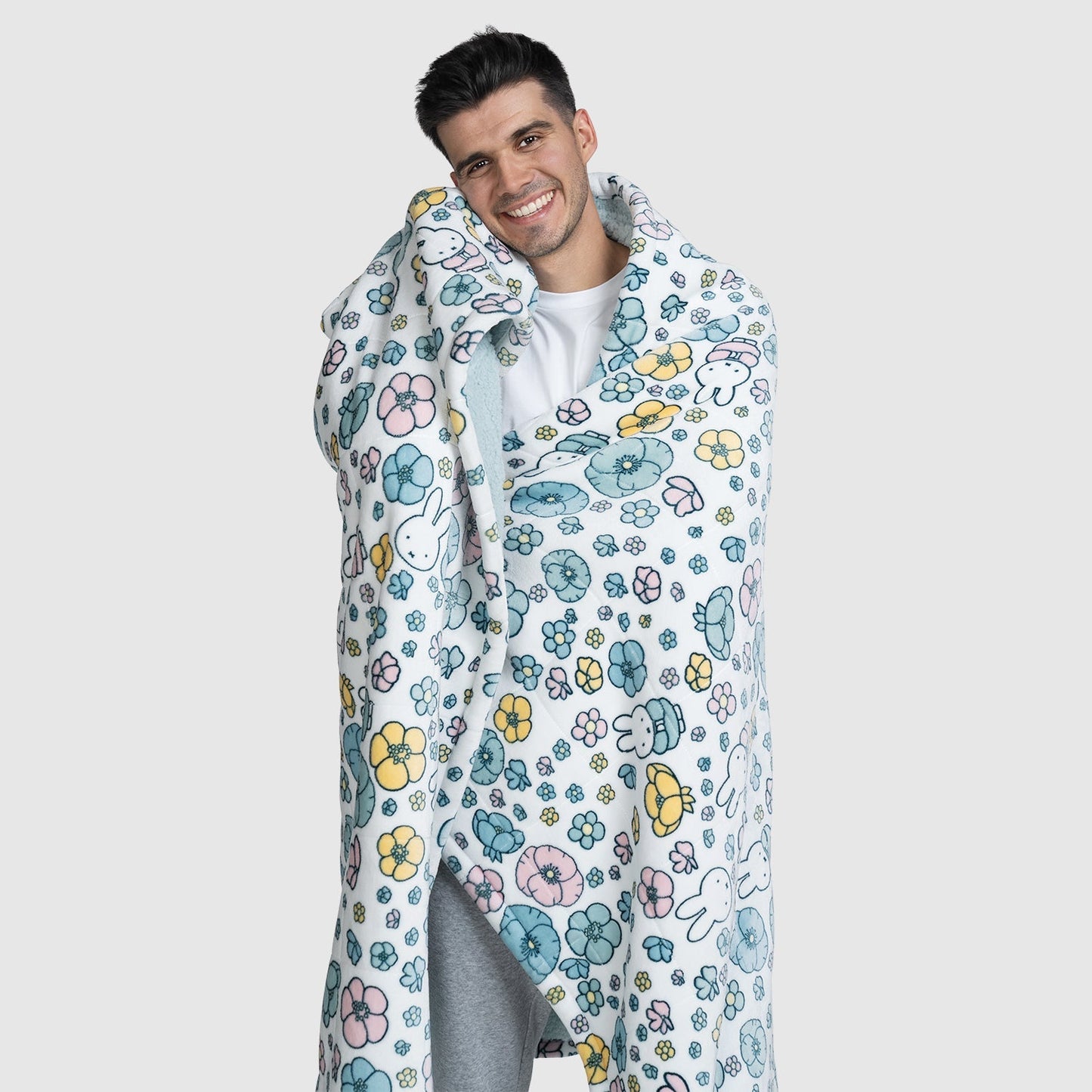 Smiling man wrapped in a blanket with a colorful floral and bunny pattern