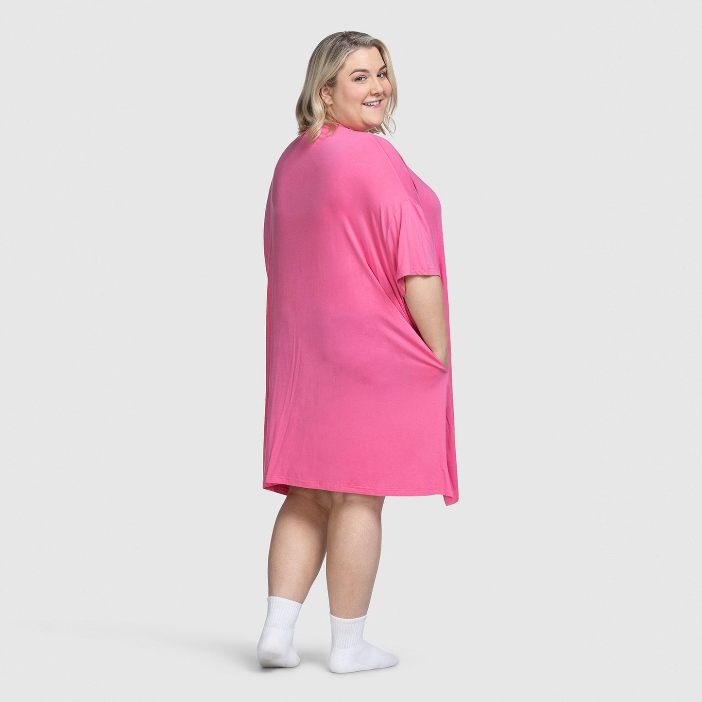 Woman wearing a bright pink dress, standing and looking over her shoulder