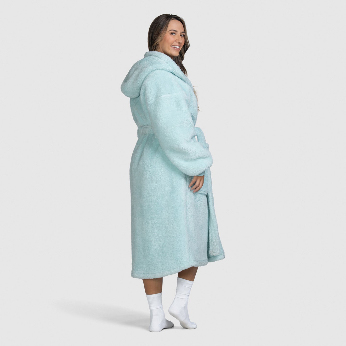 Woman wearing a light blue hooded robe standing and smiling, shown from the side