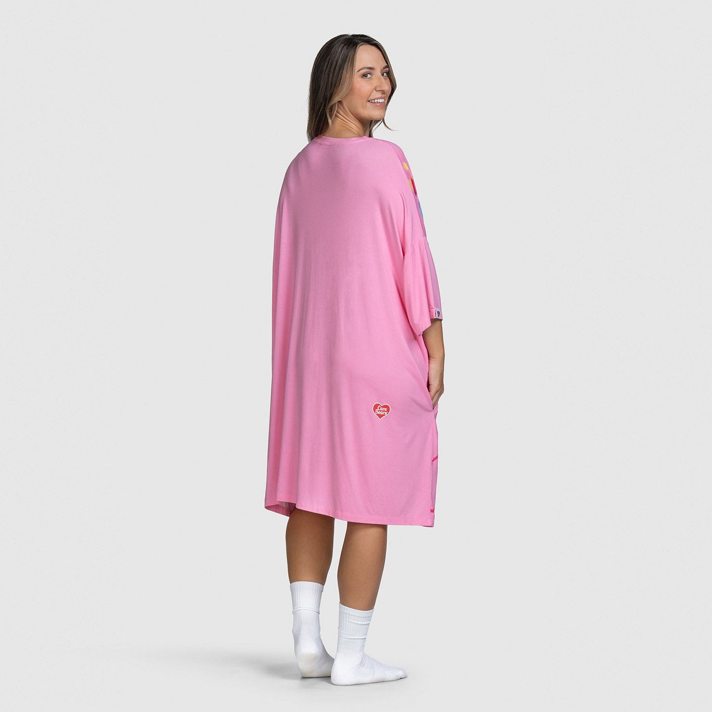 Woman wearing a pink Care Bears-themed dress, facing backward and smiling