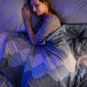 Woman sleeping peacefully under a blue and gray blanket, illustrating comfort and warmth