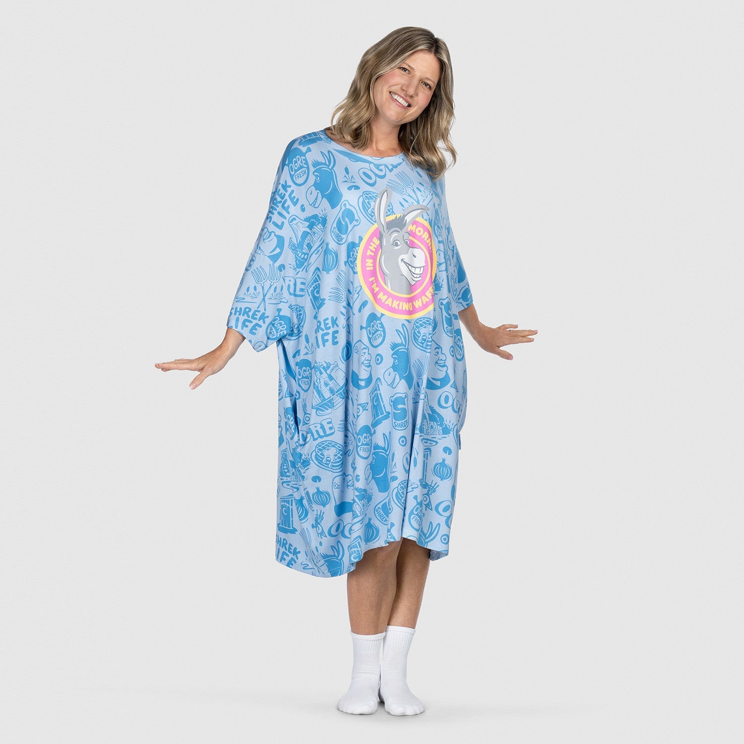 Woman wearing a blue oversized dress with a large graphic of Donkey from Shrek on the front, standing with arms slightly extended and smiling.