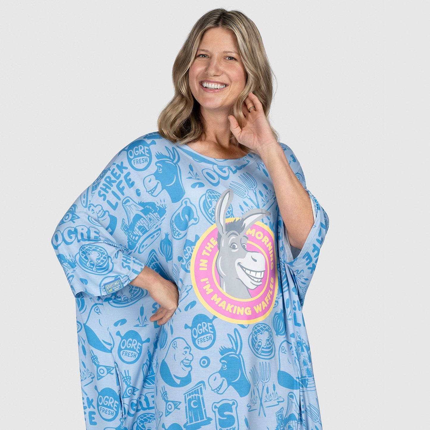Woman wearing a blue oversized shirt with Shrek and Donkey cartoon illustrations and text