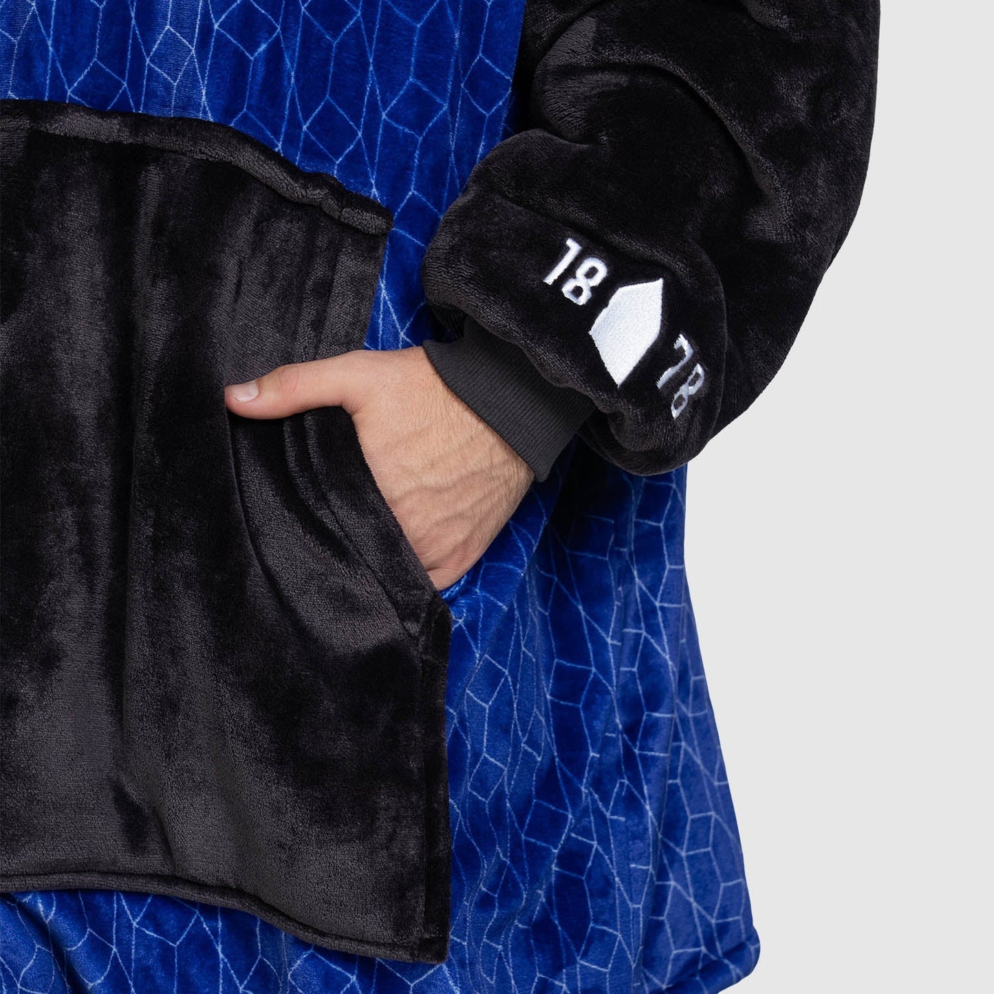 Hand in pocket of black and blue fleece with '18 78' on sleeve