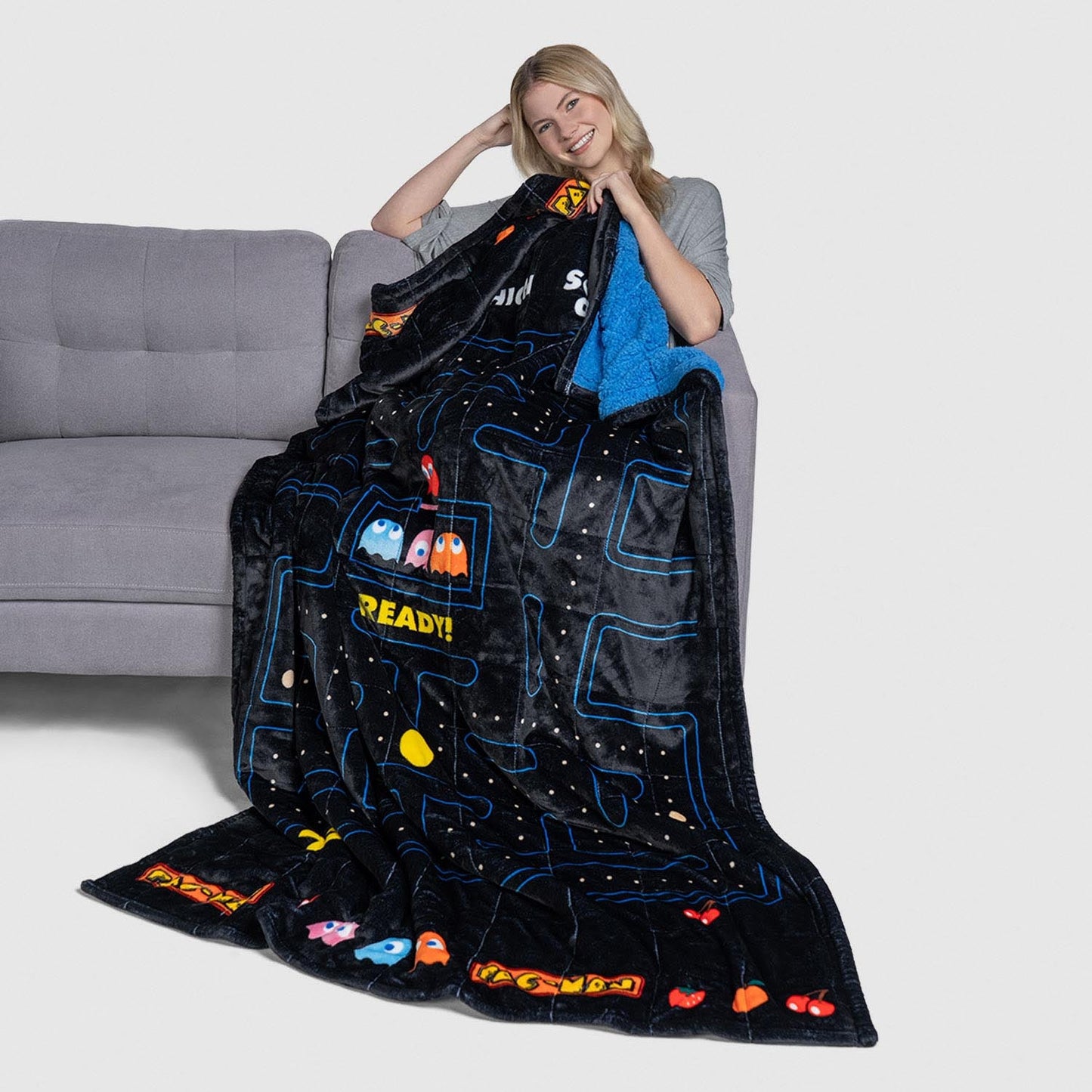 Woman holding a Pac-Man themed blanket showing characters and the word READY!