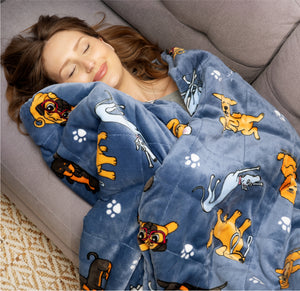 Woman resting on a couch wrapped in a blue blanket with cartoon dogs and paw prints