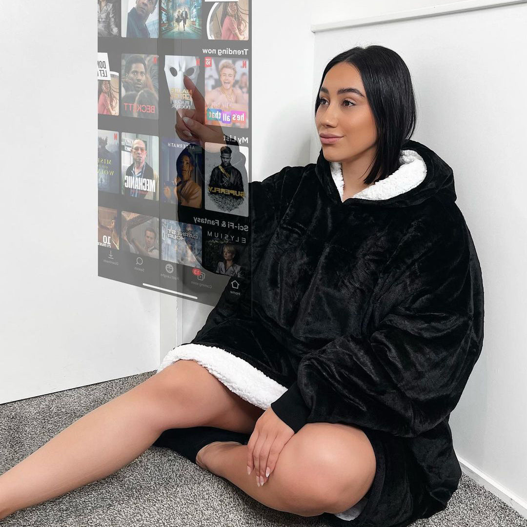 Woman sitting on carpet wearing a black and white oversized hoodie with hood up