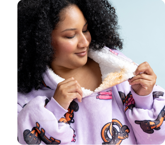 Woman wearing a purple fleece garment with dog patterns, showing its soft white inner lining