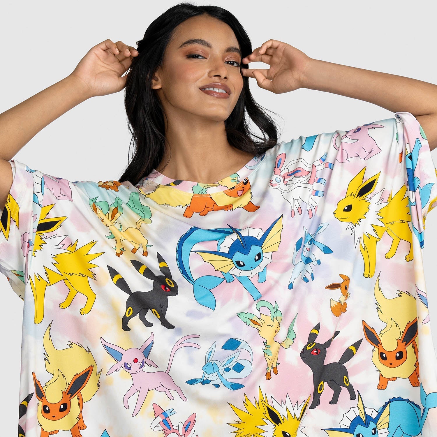 Woman wearing a colorful shirt featuring multiple Pokémon Eevee evolutions including Jolteon, Umbreon, Vaporeon, Espeon, Flareon, Leafeon, Glaceon, and Sylveon.