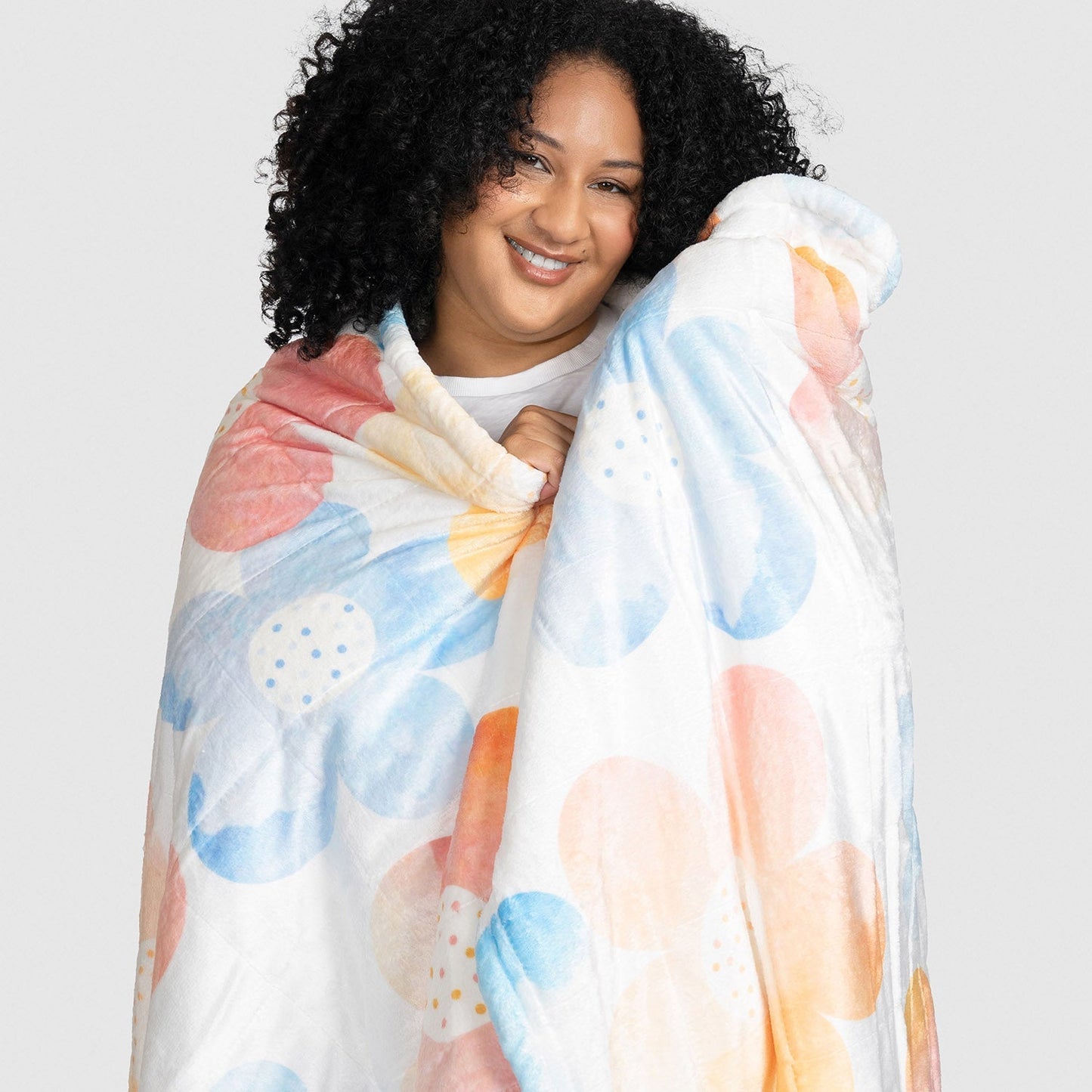 Smiling woman wrapped in a colorful floral-patterned blanket