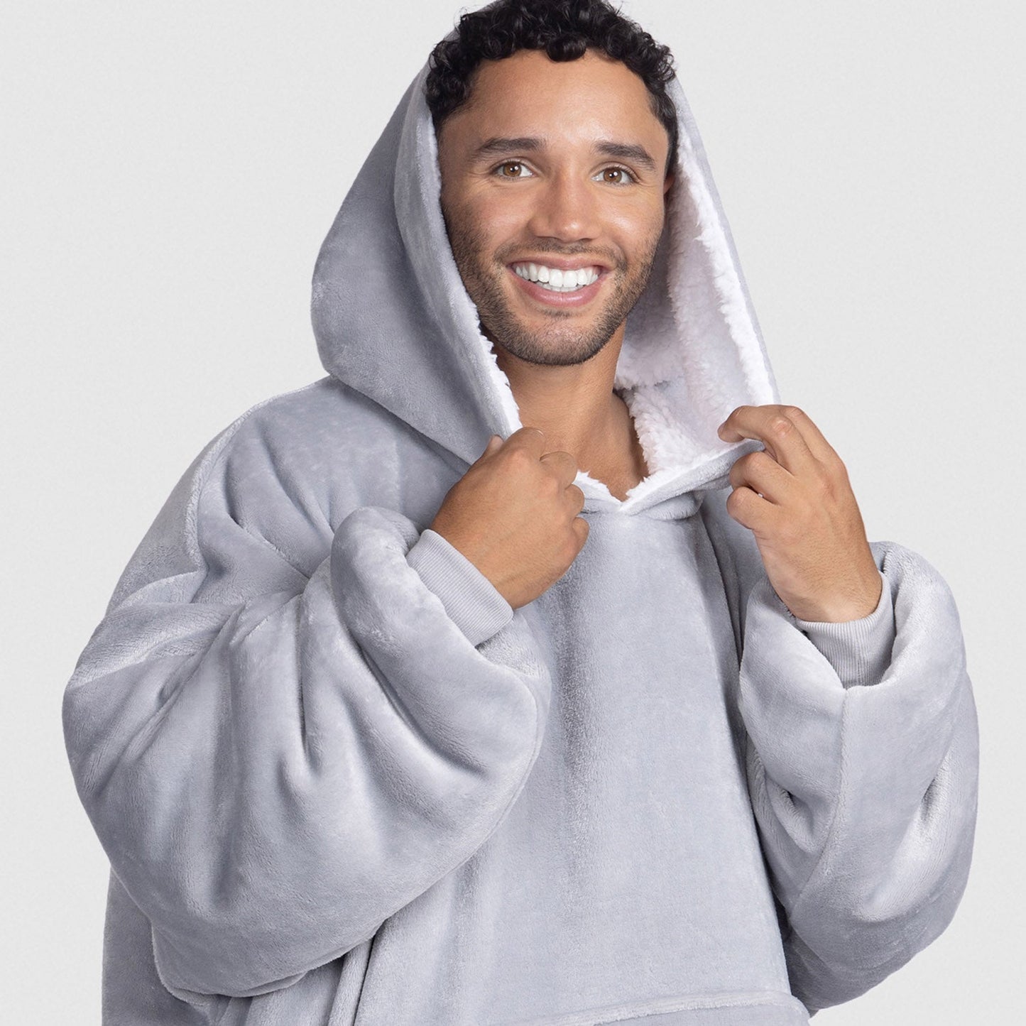 Smiling man wearing a light gray plush hooded sweatshirt with white lining