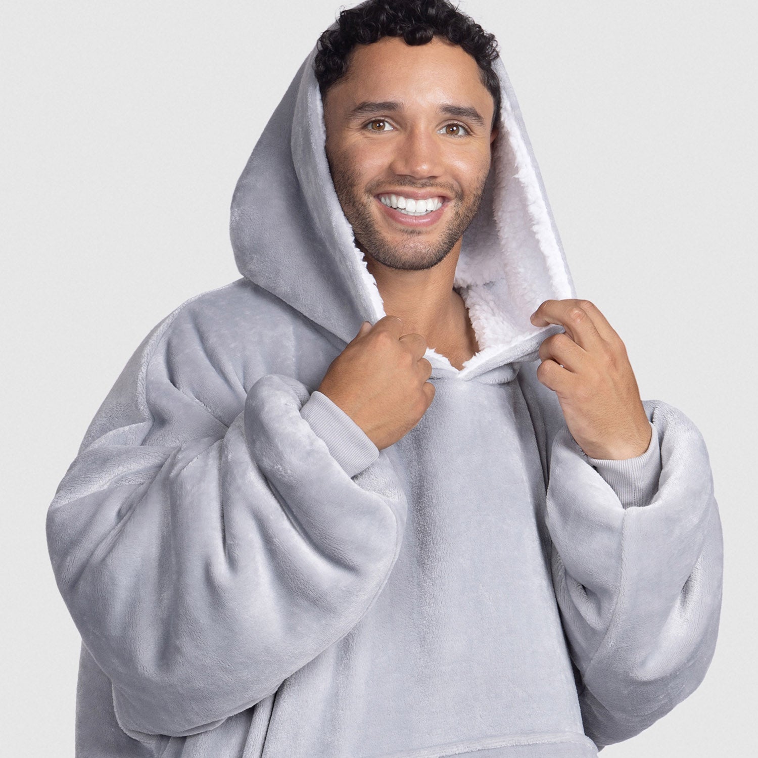 Smiling man wearing a light gray plush hooded sweatshirt with white lining