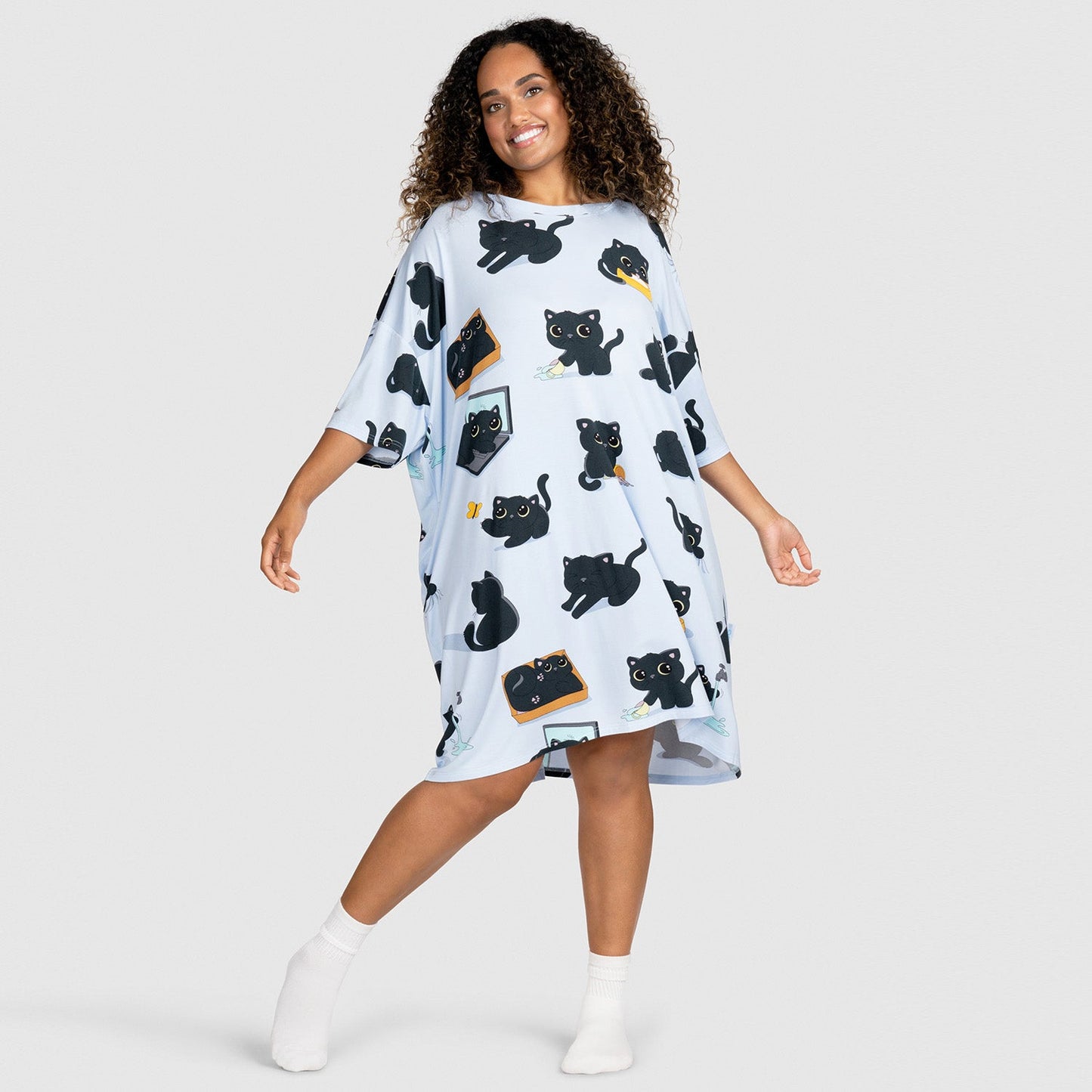 Woman wearing a light blue dress with multiple black cat illustrations in various poses
