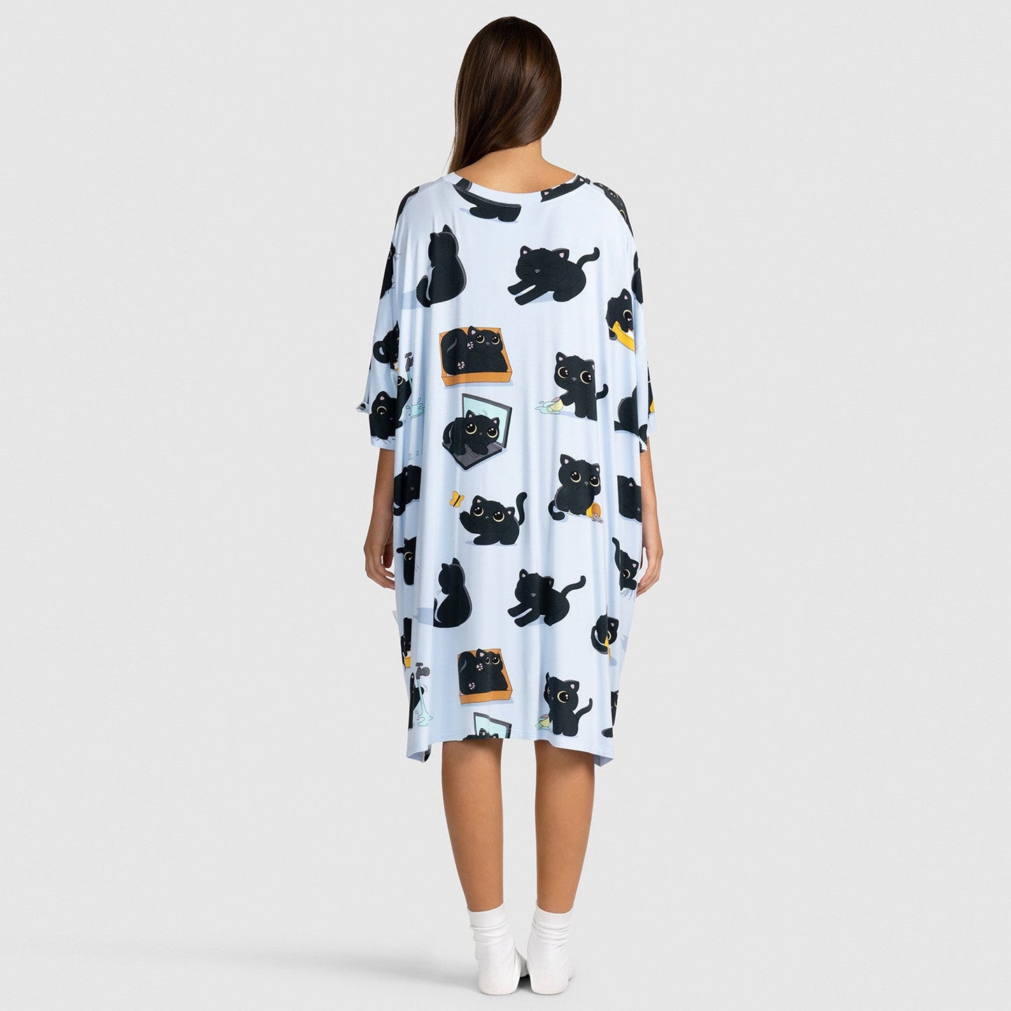 Person wearing a white dress with multiple black cat illustrations in various poses, viewed from the back.