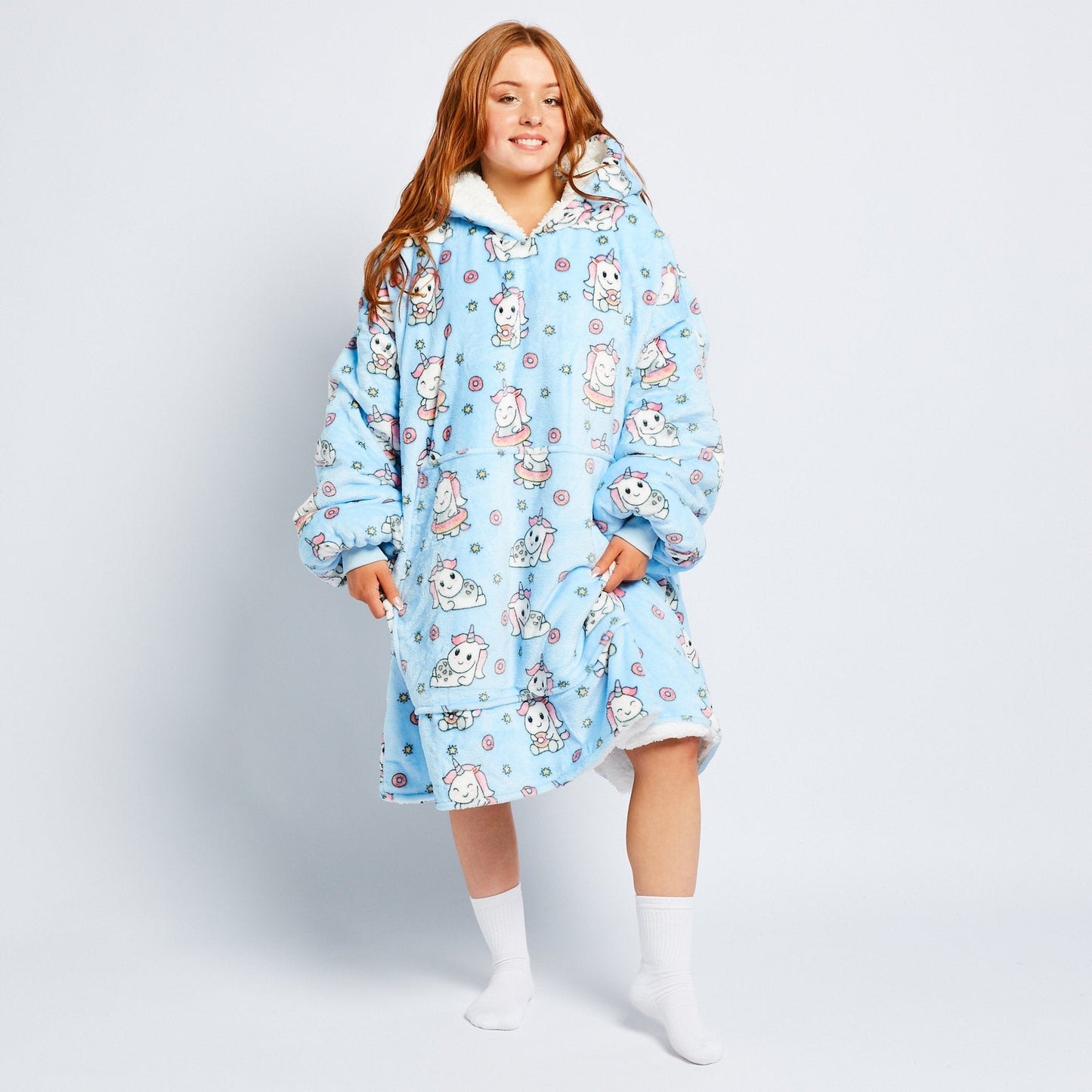 Woman wearing a blue oversized hoodie blanket with unicorn and donut patterns