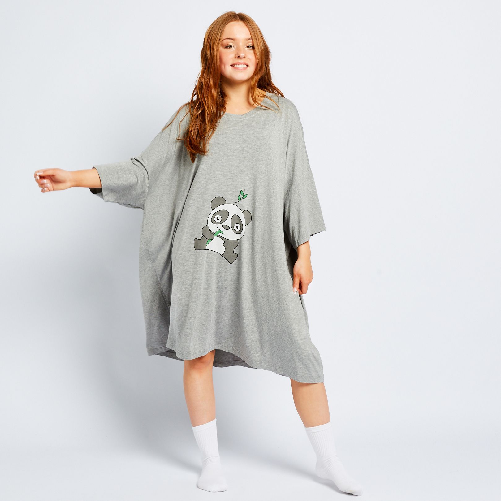 Woman wearing a loose gray dress with a cartoon panda holding bamboo printed on the front.