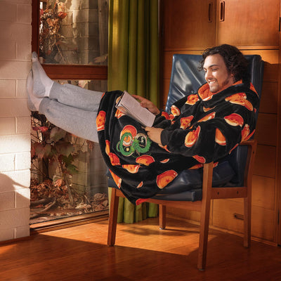 Man reading a book while wearing a black robe with Shenron and Dragon Ball patterns, sitting in a chair with feet up.