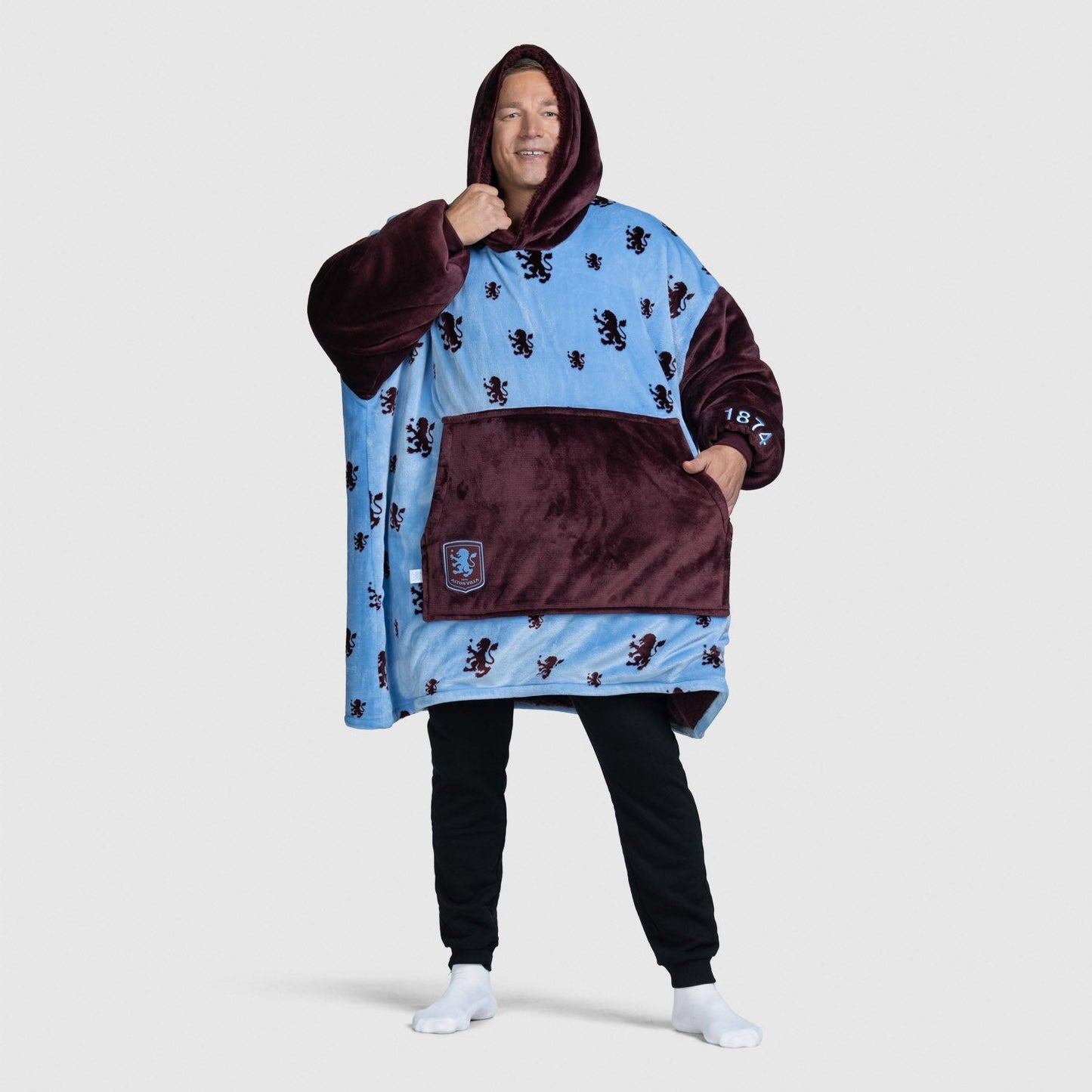 Man wearing a blue and maroon hooded wearable blanket with lion patterns, standing with one hand in pocket size: Steven is 6” wearing a size OOD