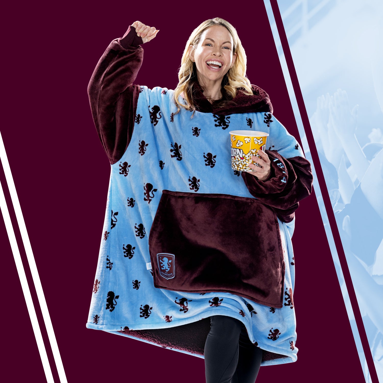 Woman wearing a blue and maroon fleece blanket with lion patterns holding a popcorn bucket