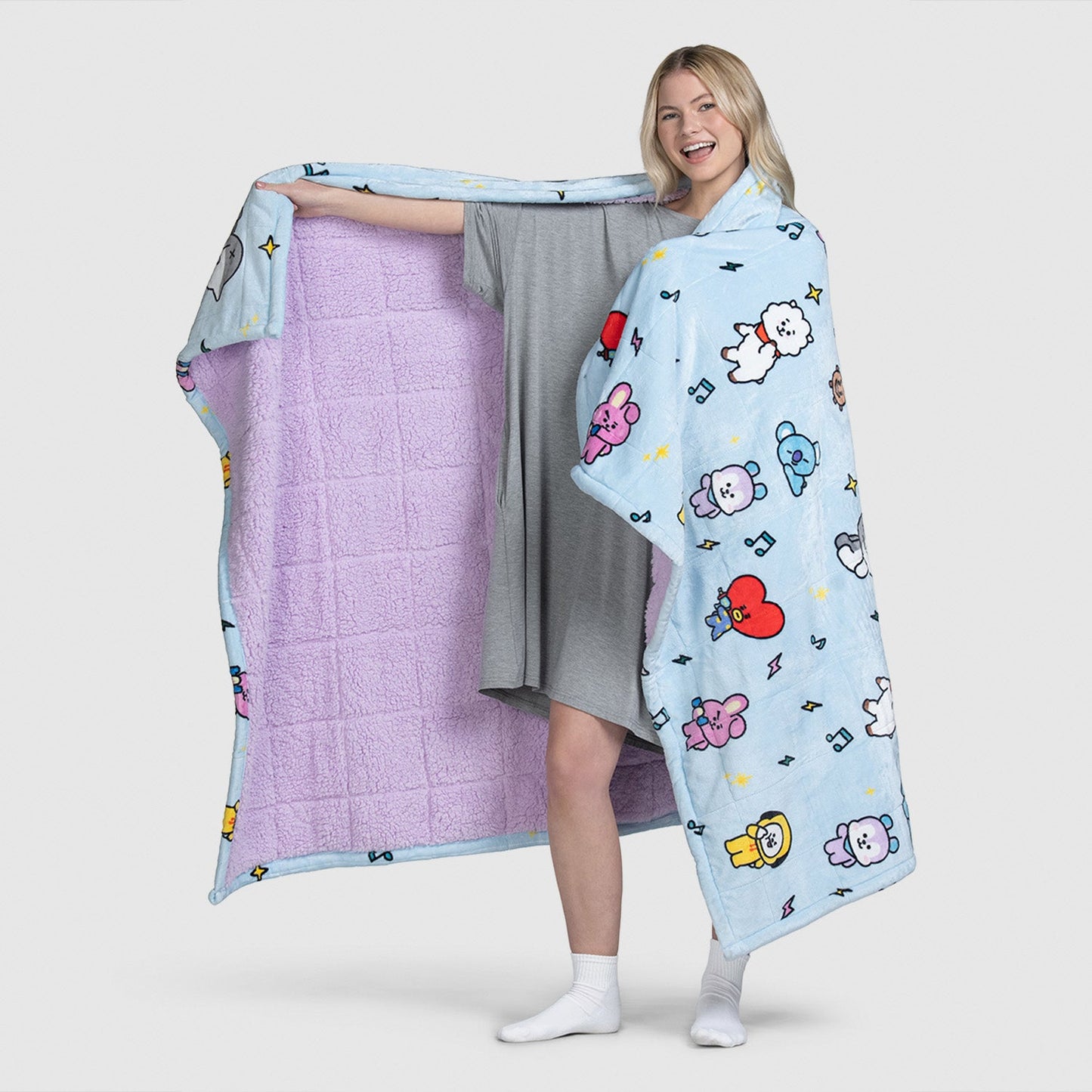 Woman holding and wearing a blue BT21 character-themed blanket with purple interior