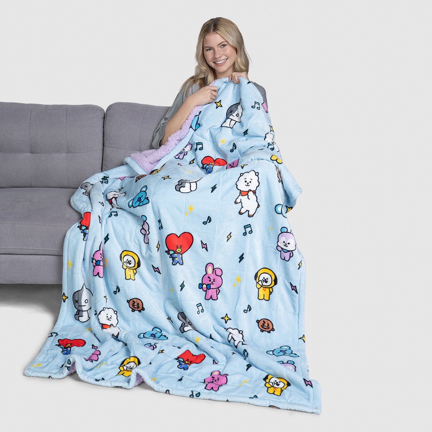 Woman holding a blue blanket with colorful BT21 cartoon characters printed on it