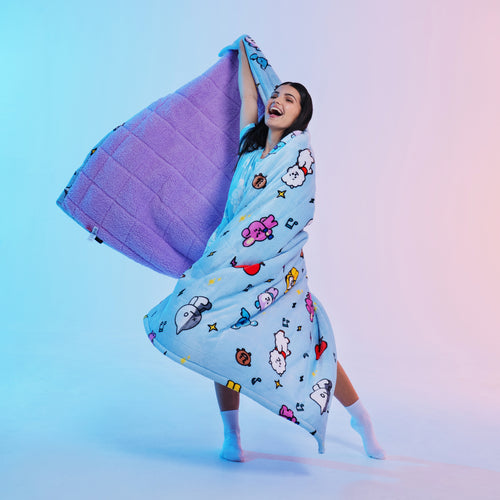 Woman wrapped in a blue blanket with colorful cartoon characters, smiling and dancing.