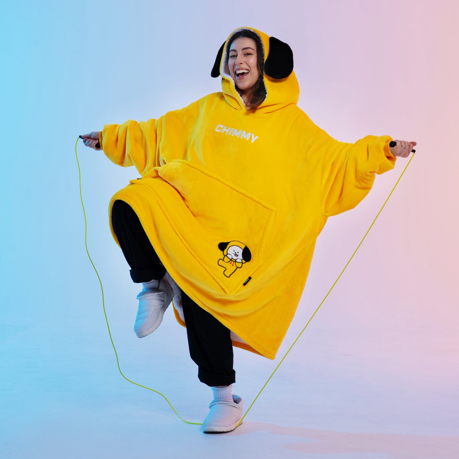 Person wearing a yellow BT21 Chimmy hoodie jumping rope with a joyful expression