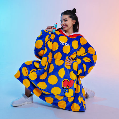 Woman wearing oversized blue hoodie with yellow polka dots and Tata character, holding a small Tata figure