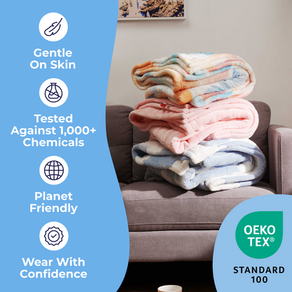 Folded blankets on chair with text: Gentle On Skin, Tested Against 1,000+ Chemicals, Planet Friendly, Wear With Confidence, OEKO TEX Standard 100