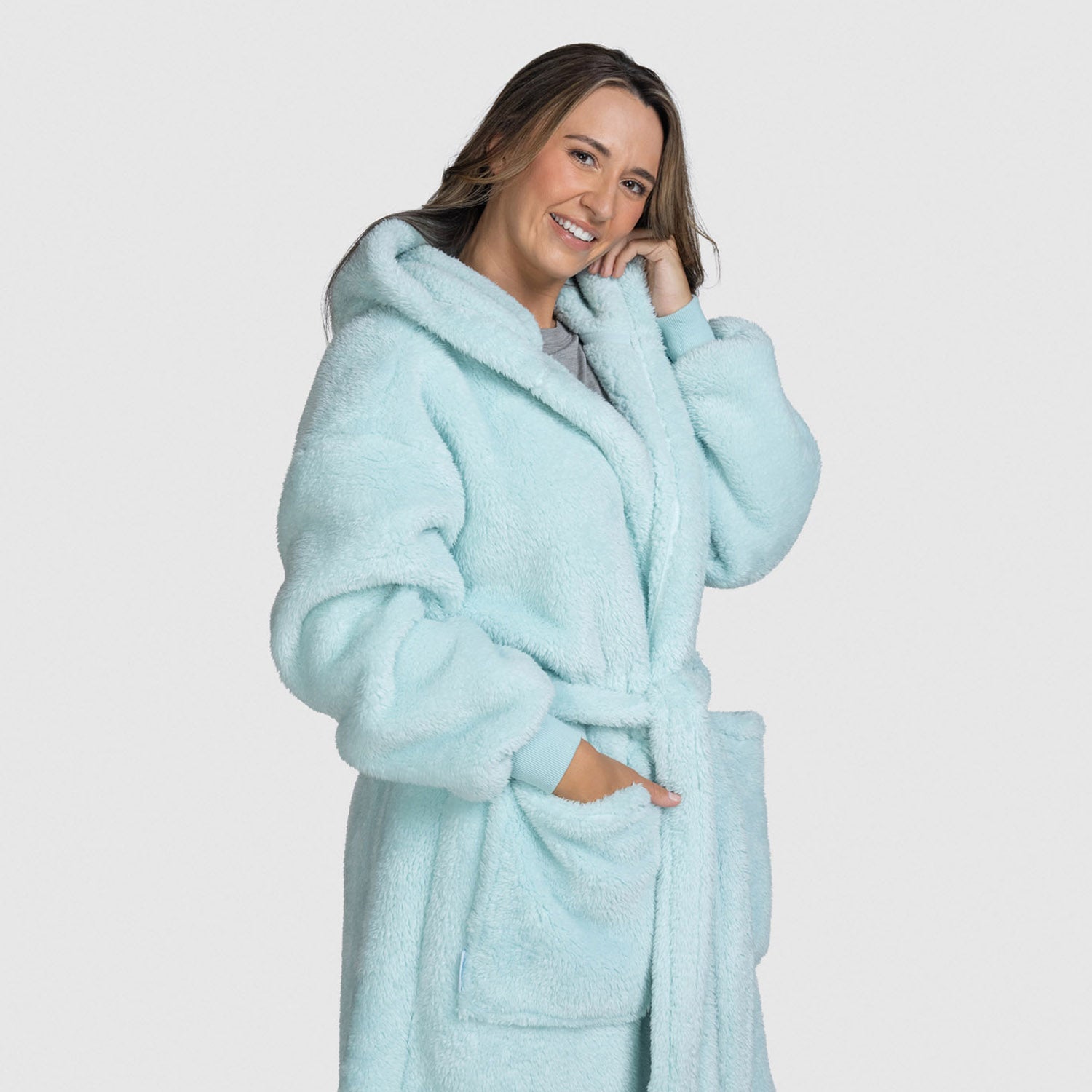 Smiling woman wearing a light blue fluffy bathrobe with pockets and a hood