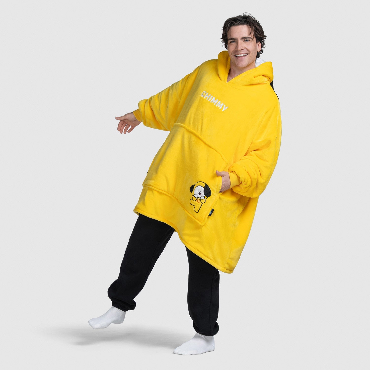 Person wearing a yellow oversized hoodie with 'CHIMMY' text and a Chimmy character patch, smiling and posing.
