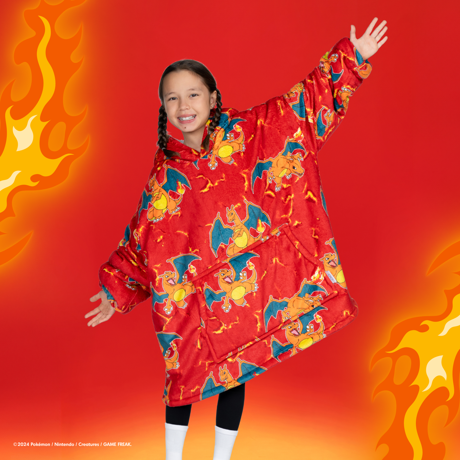 Girl wearing a red oversized hoodie covered in multiple Charizard Pokémon prints, standing with arms outstretched against a red background with flame graphics.