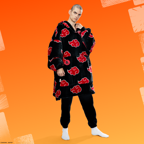 Person wearing a black oversized hoodie with red cloud patterns inspired by Akatsuki from Naruto, standing against an orange background.