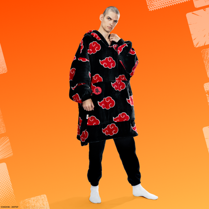 Person wearing a black oversized hoodie with red cloud patterns inspired by Akatsuki from Naruto, standing against an orange background.
