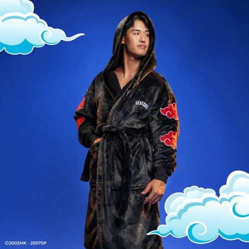 Man wearing a black hooded robe with red cloud patterns on the sleeves and chest, standing against a blue background with stylized clouds.