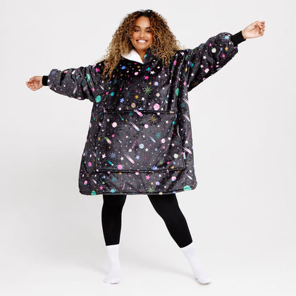 Smiling woman wearing a black oversized hoodie with colorful space-themed planets, stars, and comets pattern