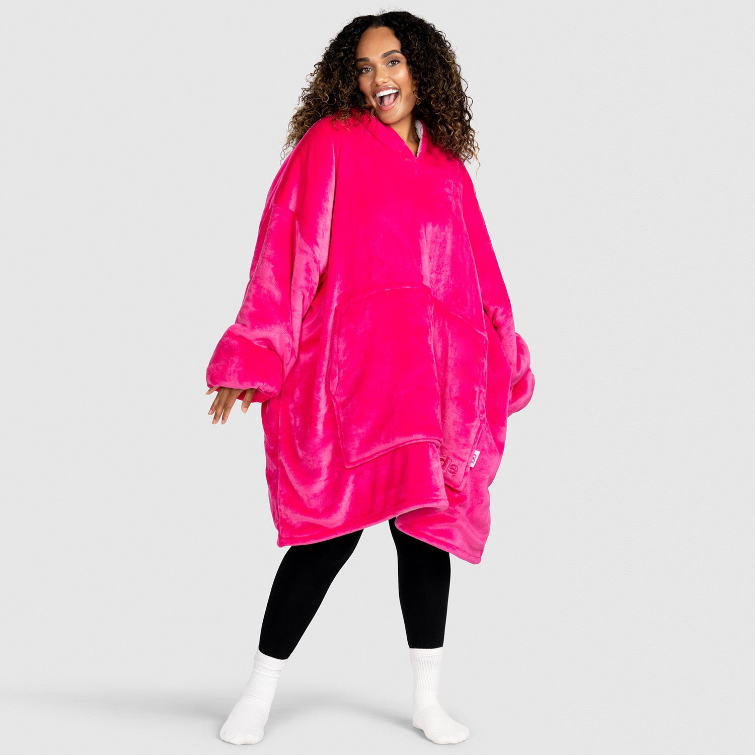 Woman smiling and wearing a bright pink oversized wearable blanket hoodie