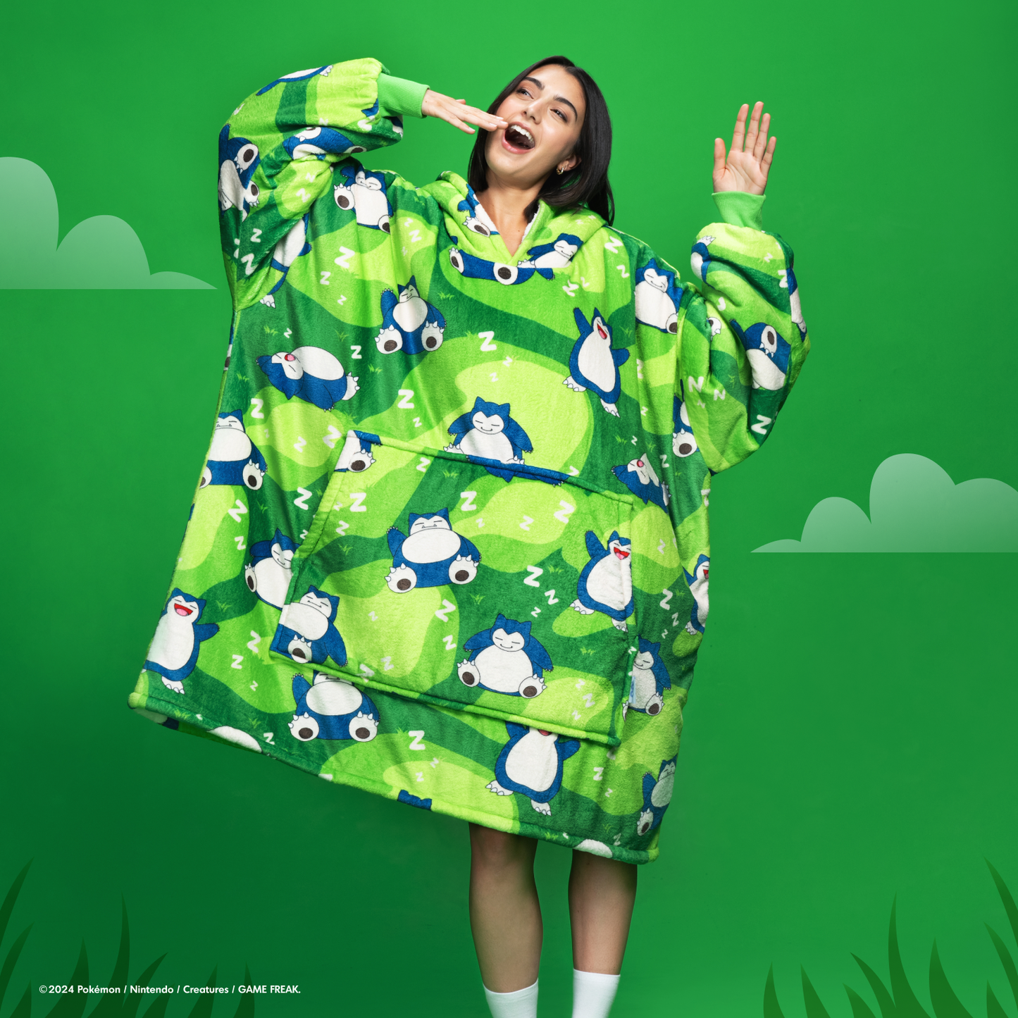 Person wearing a green Snorlax-themed wearable blanket with a front pocket and a green background