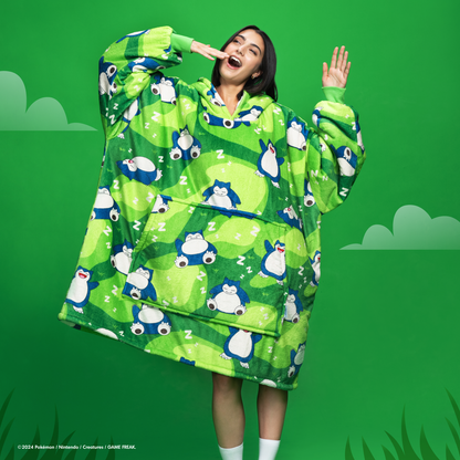 Person wearing a green Snorlax-themed wearable blanket with a front pocket and a green background