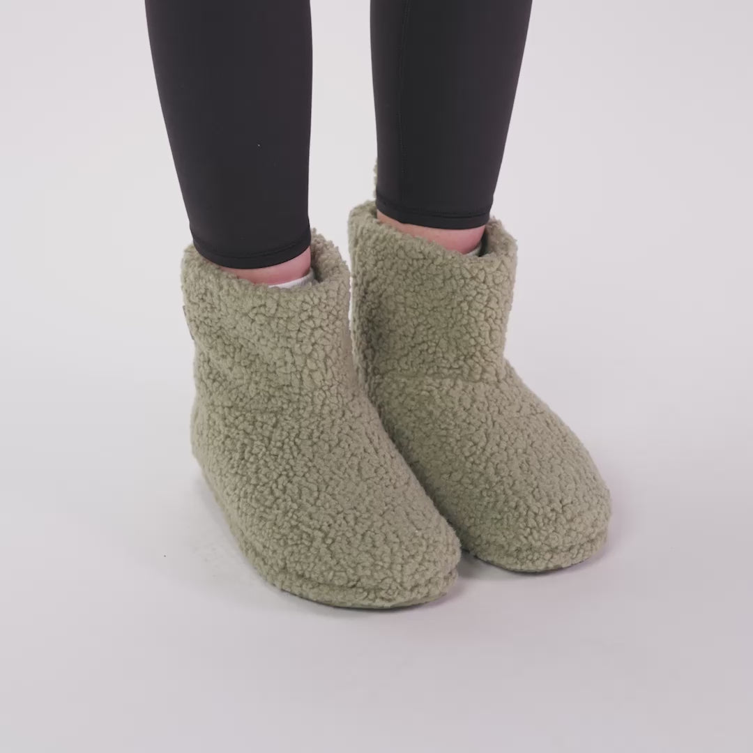 Light green sherpa-style slipper boots worn on feet