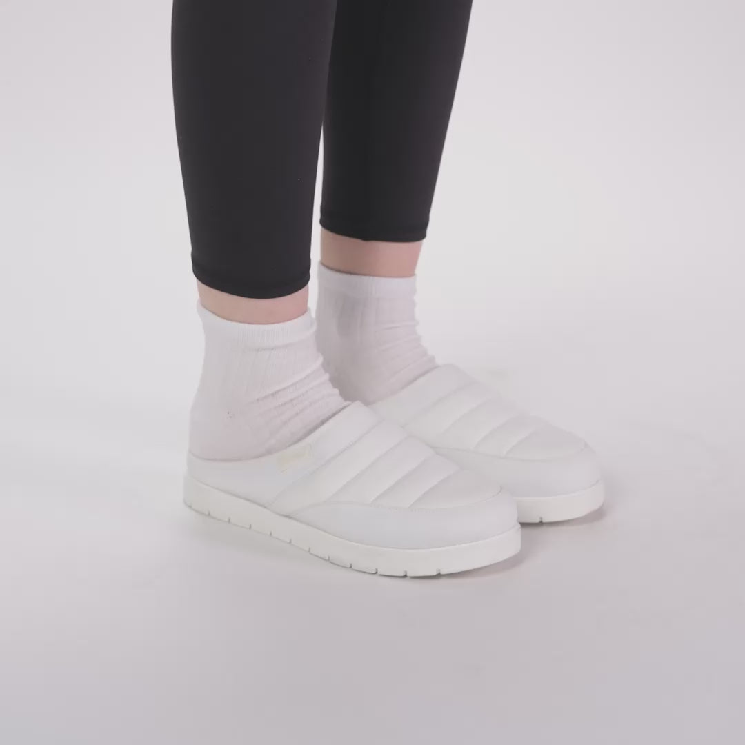 White puffer slip-on shoes worn with white socks and black leggings