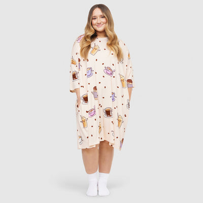 Woman wearing a cream-colored dress with coffee cup and dessert prints, standing and smiling, wearing white socks.