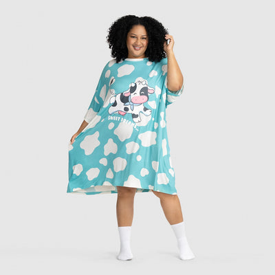 Woman wearing a blue dress with white cow spots and a cartoon cow with the text 'SWEET DREAMS' printed on the front