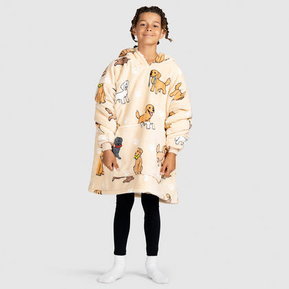Child wearing a beige oversized hoodie with cartoon retriever dog prints, black leggings, and white socks, standing against a plain background.